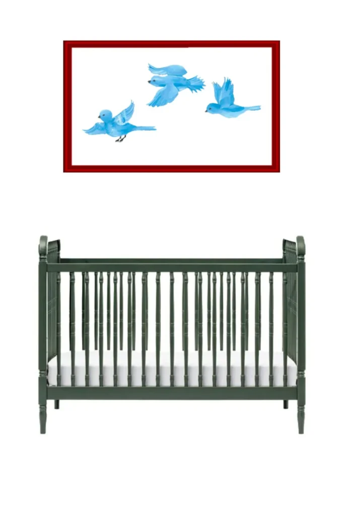 A dark green baby crib under a framed picture of blue birds.